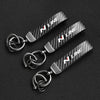 A set of three black carbon fiber style keychains with silver hardware displayed on a dark background.