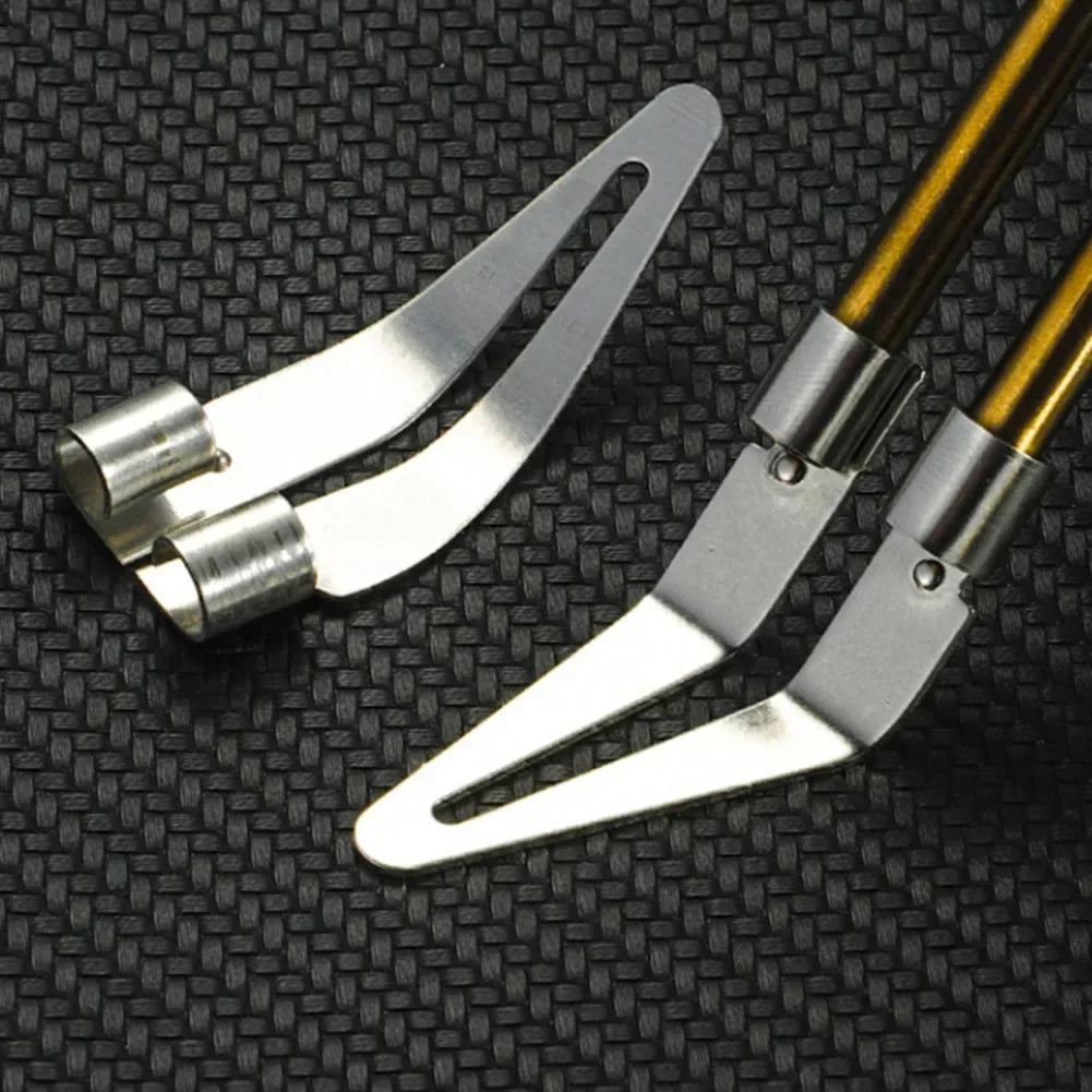 A pair of silver precision plastic welding and repair tools with gold-colored handles resting on a black textured surface.