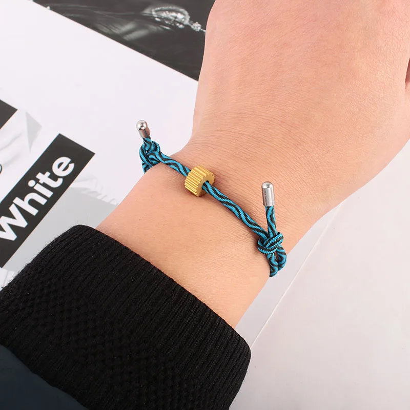 A hand wearing a blue braided fitness tracker bracelet with a gold accent, shown against a white background.