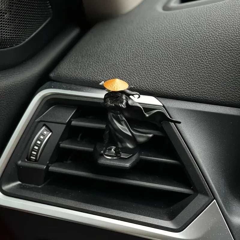 A black samurai statue with an orange head is displayed in a car interior console.