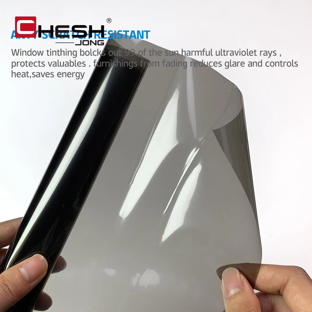 Une main tient un film de teinte automobile foncé, montrant sa surface brillante.