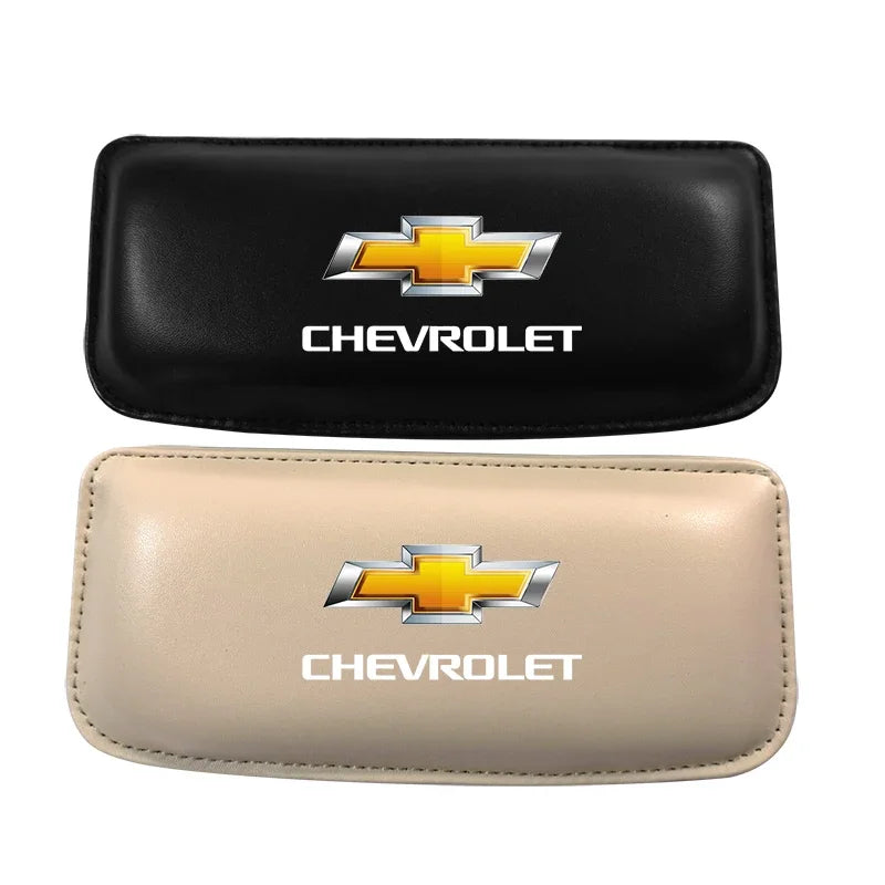 A pair of leather car driving knee pads, one black and one beige, featuring a Chevrolet emblem.