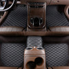 Interior view of a car with dark brown quilted floor mats and leather seats.