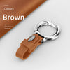 A brown cowhide leather keychain with a silver split ring and a leather strap is shown on a white background.