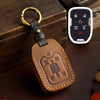A brown leather key cover with a brass ring attached, featuring embossed symbols for Chevrolet and GMC trucks.