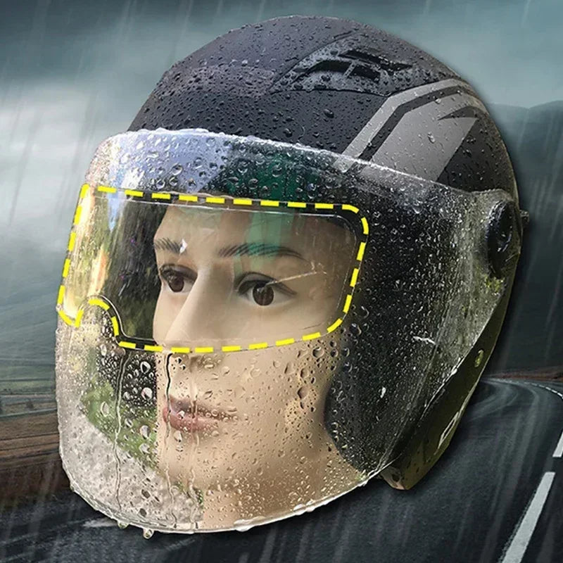 A close-up of a motorcycle helmet visor showing water droplets and fog protection film.