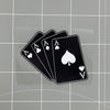 A set of black playing cards, including aces and a jack of hearts, resting on a transparent surface.