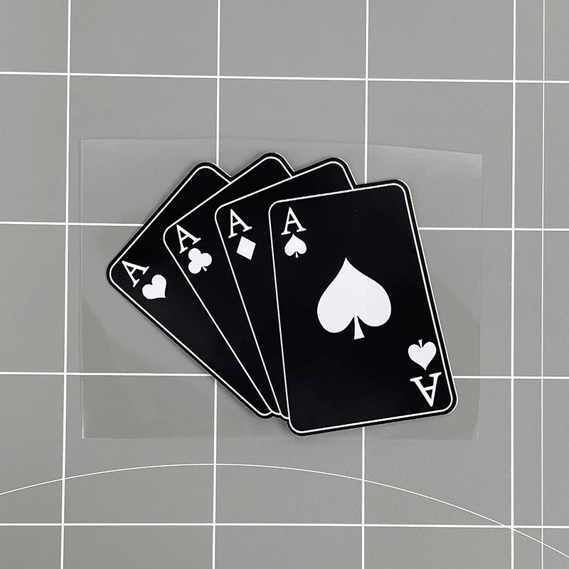 A set of black playing cards, including aces and a jack of hearts, resting on a transparent surface.