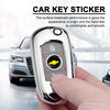 A hand holds a silver car key sticker, showing the key emblem and surface treatment.