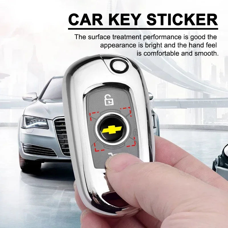A hand holds a silver car key sticker, showing the key emblem and surface treatment.