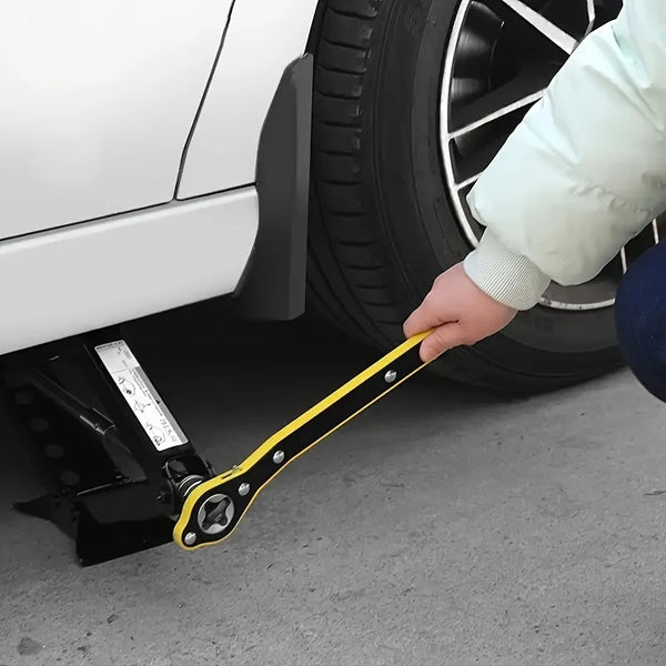 A hand is using a yellow heavy-duty ratchet wrench to service a tire or jack on a white vehicle.