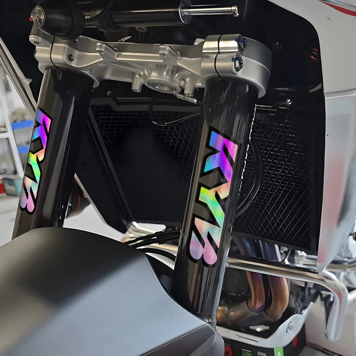 Close-up of motorcycle racing suspension components featuring colorful decals and polished metal parts.