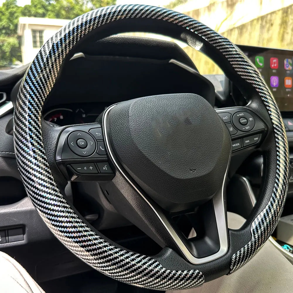 Nahaufnahme eines schwarzen Lenkrads mit karierter Kohlefaserabdeckung im Autointerieur.