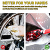 A close-up of a hand using a red detailing brush to clean dirt from a car wheel.