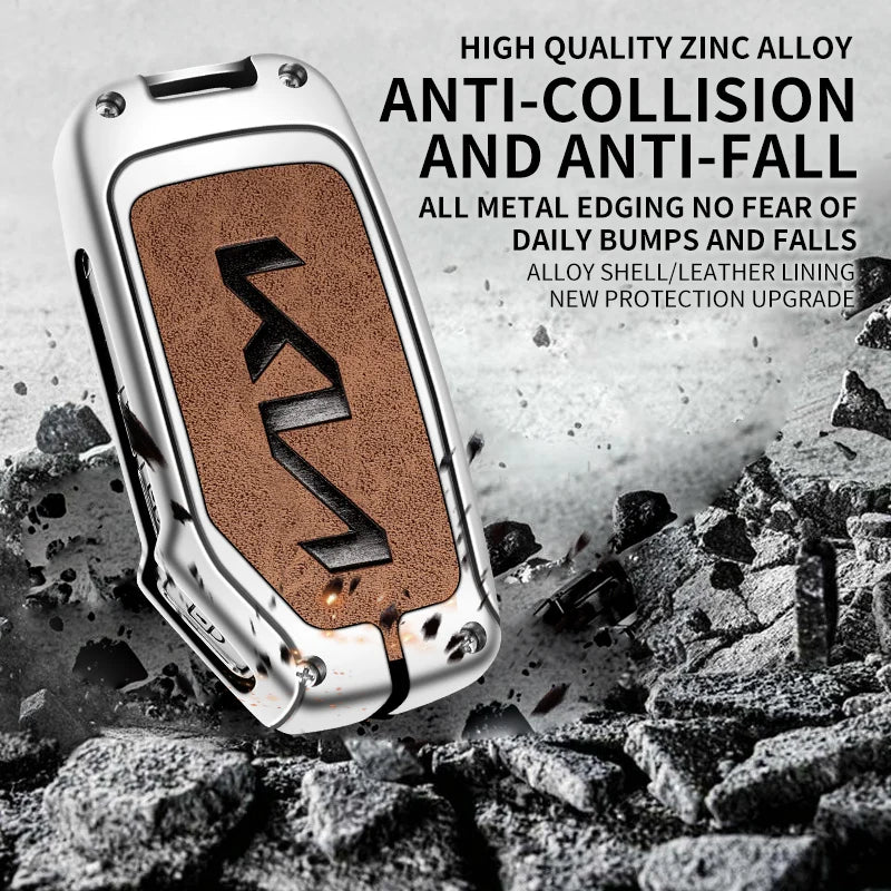 A silver metal car key case with a textured brown insert is shown against a background of dark rocks and debris.