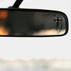 A close-up of a black car mirror with a gothic thorn cross decal on the surface.