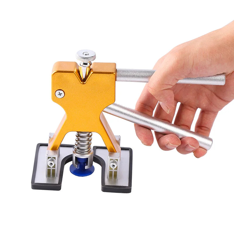 A hand is operating a professional plastic dent puller kit for auto repair, showing the tool's mechanism.