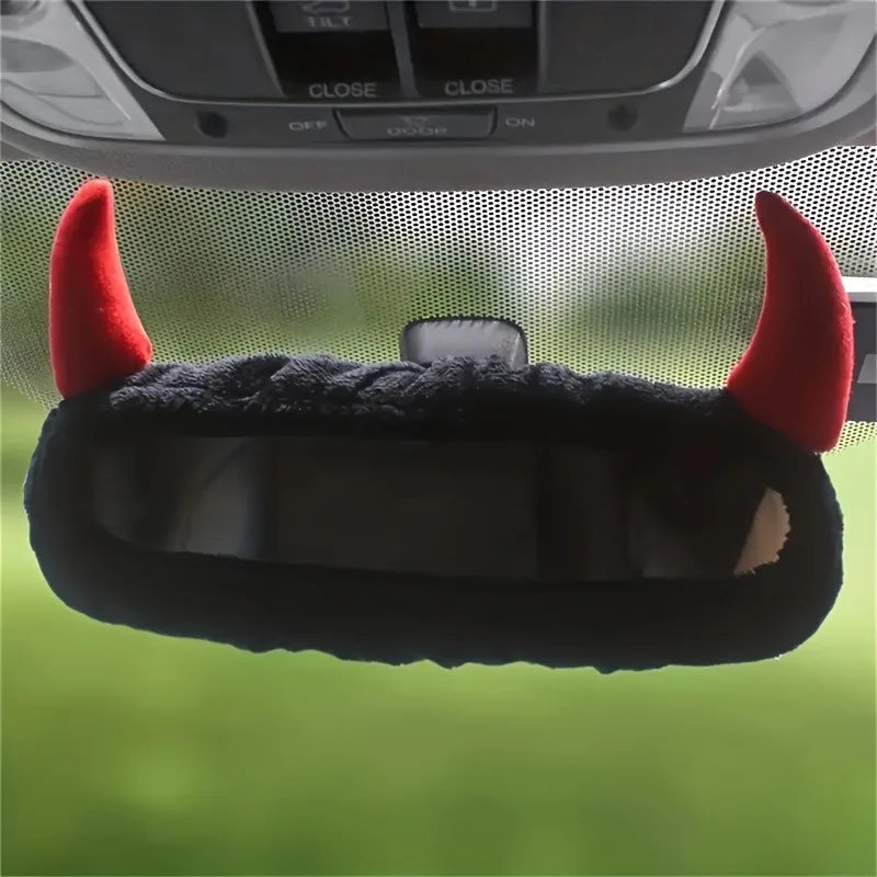 Couverture de miroir en corne de diable noire et duveteuse avec des accents rouges, sur fond vert flou.
