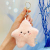 A pink fluffy cloud shaped plush bunny keychain with a gold ring being held by a hand.