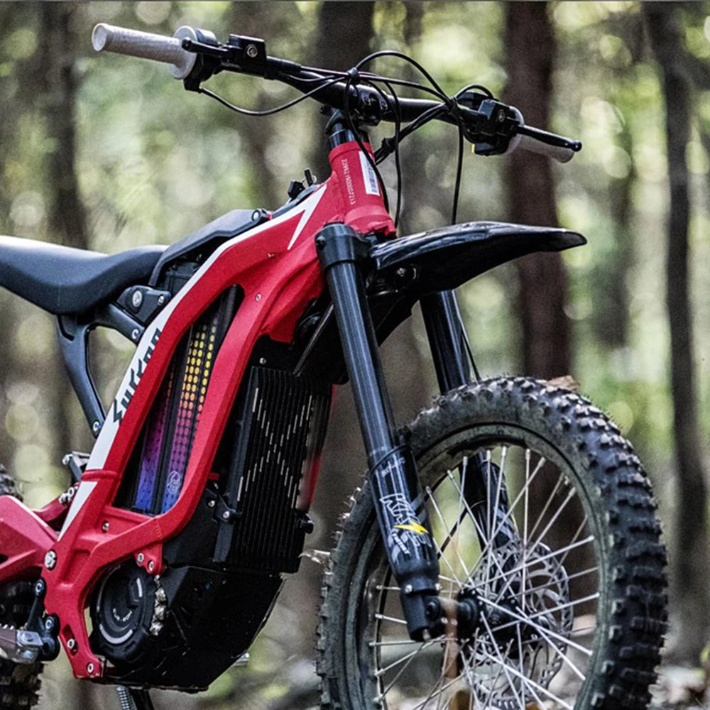 A red universal motorcycle fender for an e-bike is shown in a natural outdoor setting.