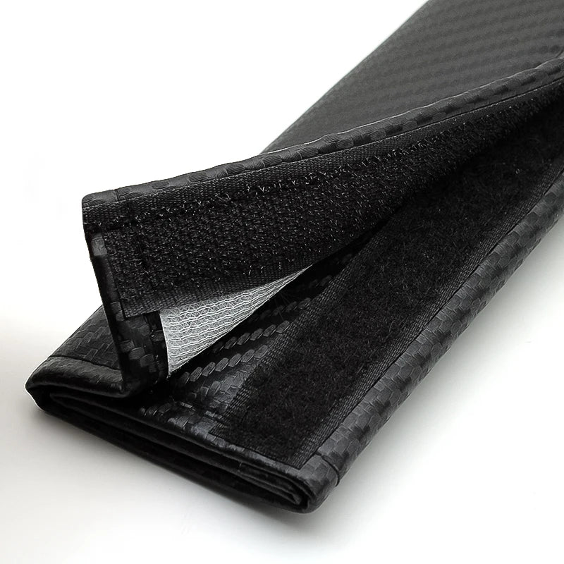 Black carbon fiber seat belt shoulder pad cover folded and laid flat