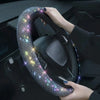 A hand is gripping a black steering wheel covered in sparkling rhinestones.