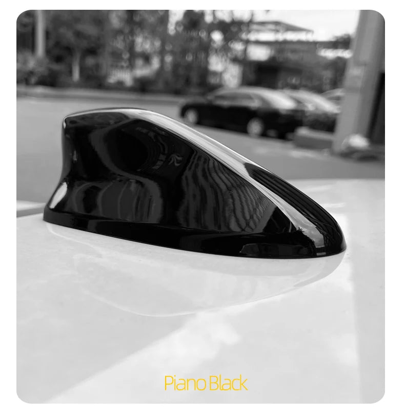 Piano Black shark fin roof antenna cover displayed on a white surface.