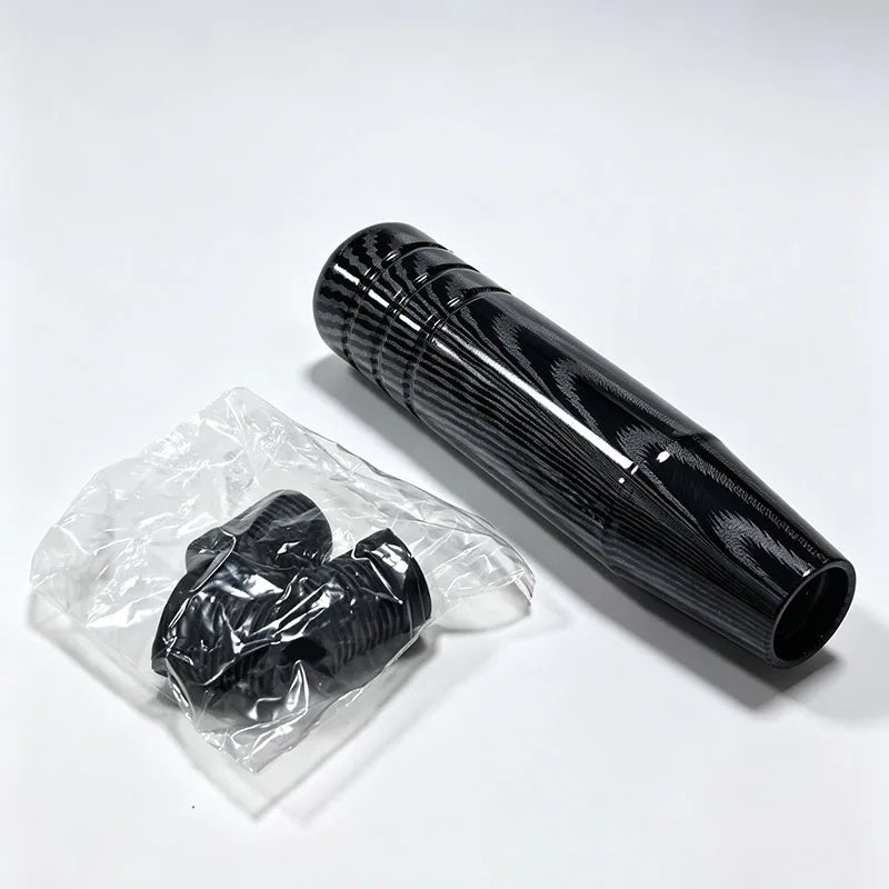 A black manual gear shift knob is shown next to its clear plastic packaging.