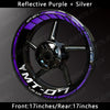 A close-up view of a motorcycle wheel featuring reflective purple and silver decals on the rim.