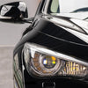 Close-up of a glossy black car featuring aftermarket headlight decals and a side mirror.