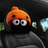 Orange gestrickte Mütze in Form eines Gesichts auf einer schwarzen Auto-Kopfstütze