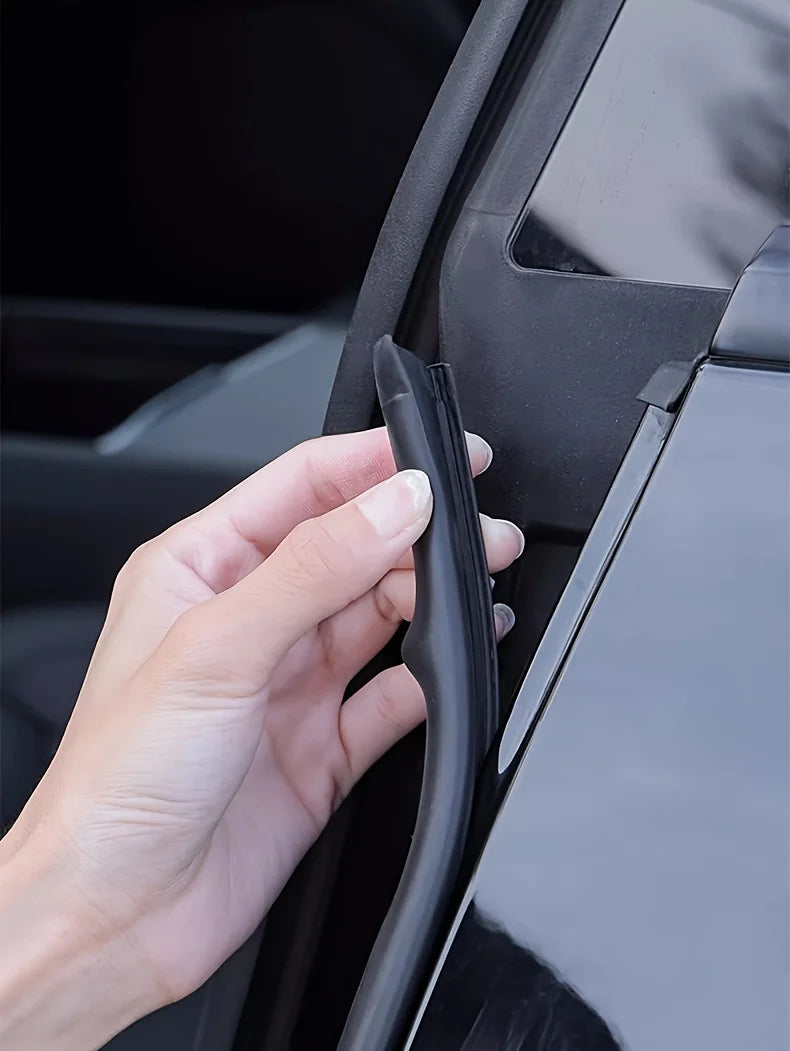 A hand is pressing a black rubber seal strip, a universal car door edge weatherstrip, into the B-pillar of a vehicle.