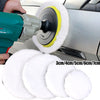 A hand is using an electric tool to attach a white polishing disc onto a silver car surface.