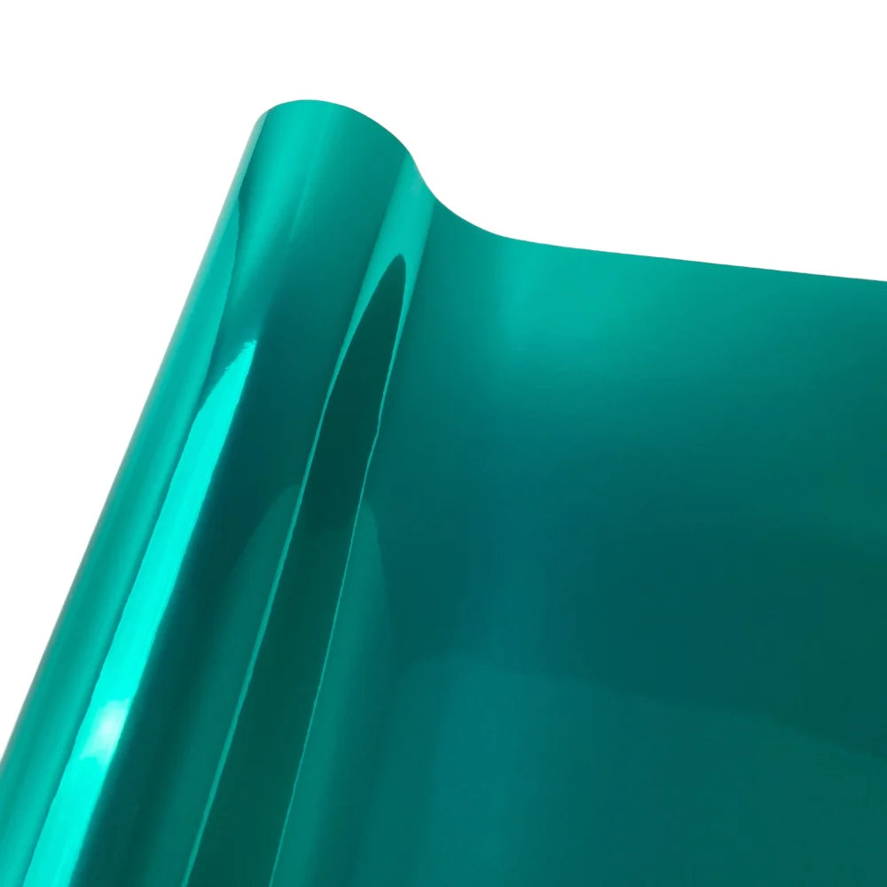 A close-up view of a glossy teal vinyl car wrap film showing its smooth, curved surface.