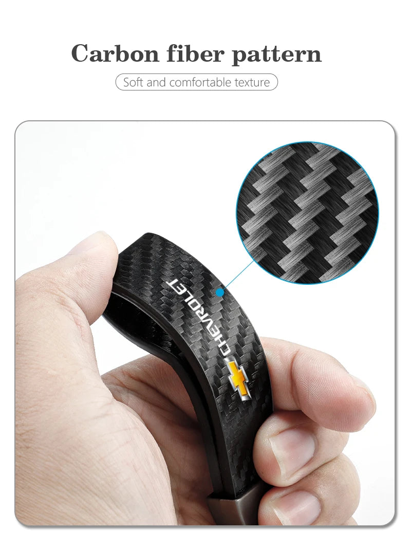 A hand holds a black carbon fiber pattern car key fob, showing its texture and design.