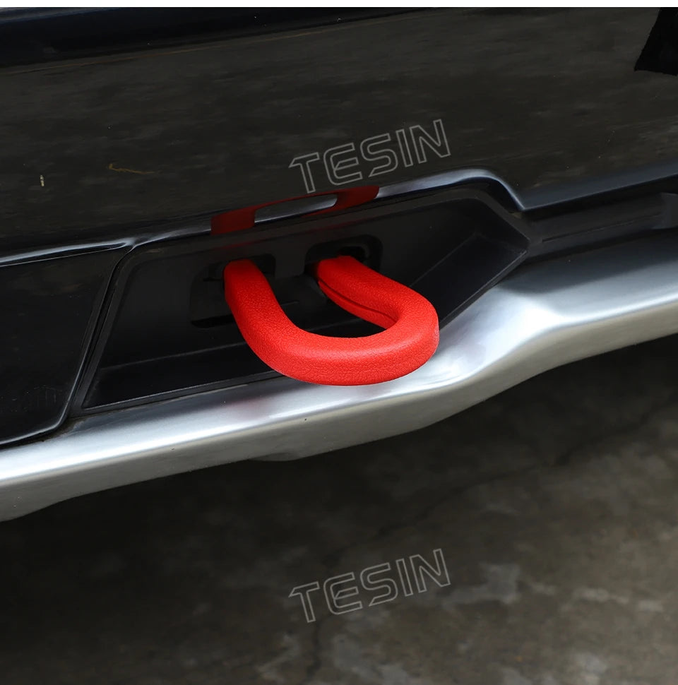 Close-up of a red tow hook cover installed on a silver car exterior bumper.