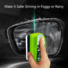 A hand is using a bright green windshield cleaning brush to wipe fog or rain off a car's windshield.