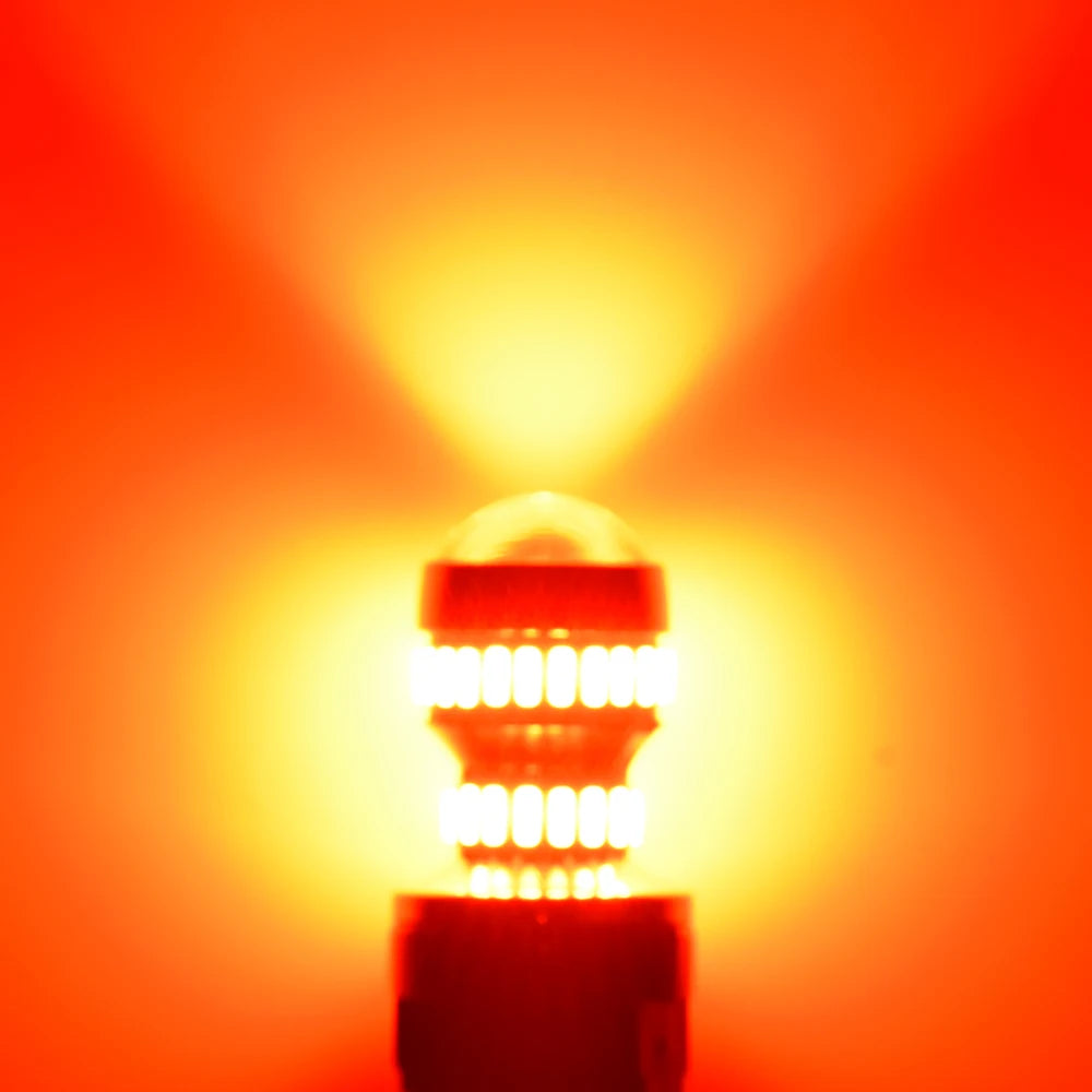 A bright LED car bulb illuminating a dark housing against an orange background.