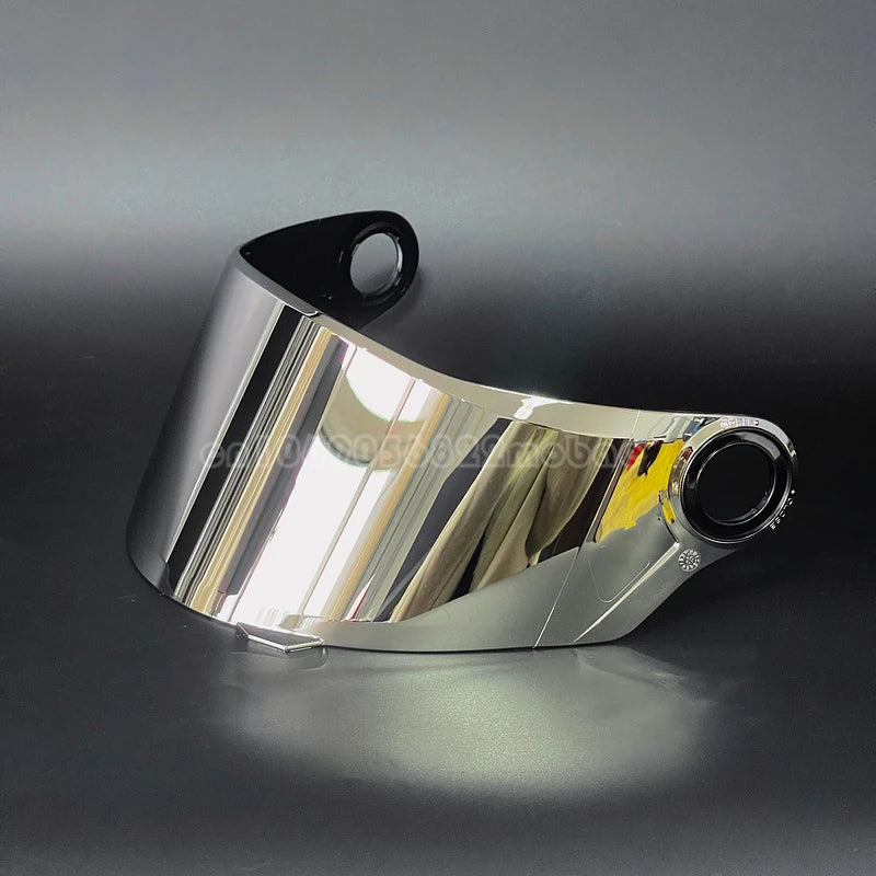 Visor de casco de motocicleta plateado con correa negra, reflejando luz en una superficie oscura.