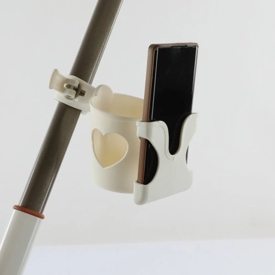 Support multifonction blanc fixé à la barre d'une poussette, tenant un smartphone dans un design de tasse.