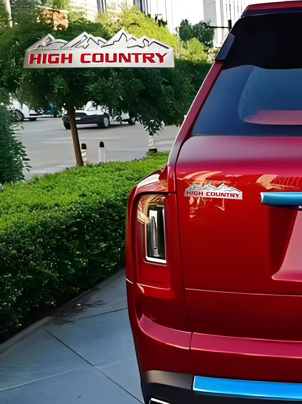 A close-up of a red truck or car with a High Country decal on the rear, parked near a sign.