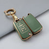A gold-toned TPU key fob case with a keyring and decorative elements, shown against a gray background.