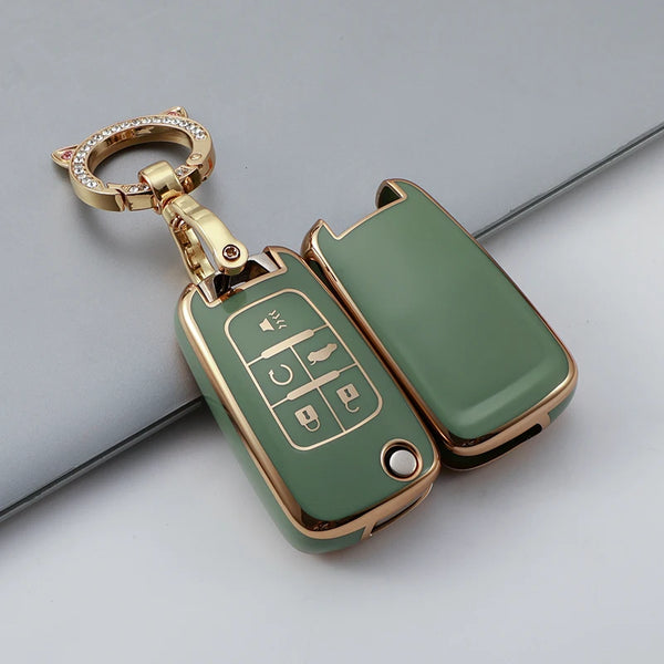 A gold-toned TPU key fob case with a keyring and decorative elements, shown against a gray background.