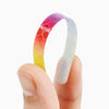 A hand holds a curved, multi-color reflective safety sticker, transitioning from orange to white.