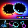 Two illuminated LED car cup holder coasters displaying various colors and light effects.