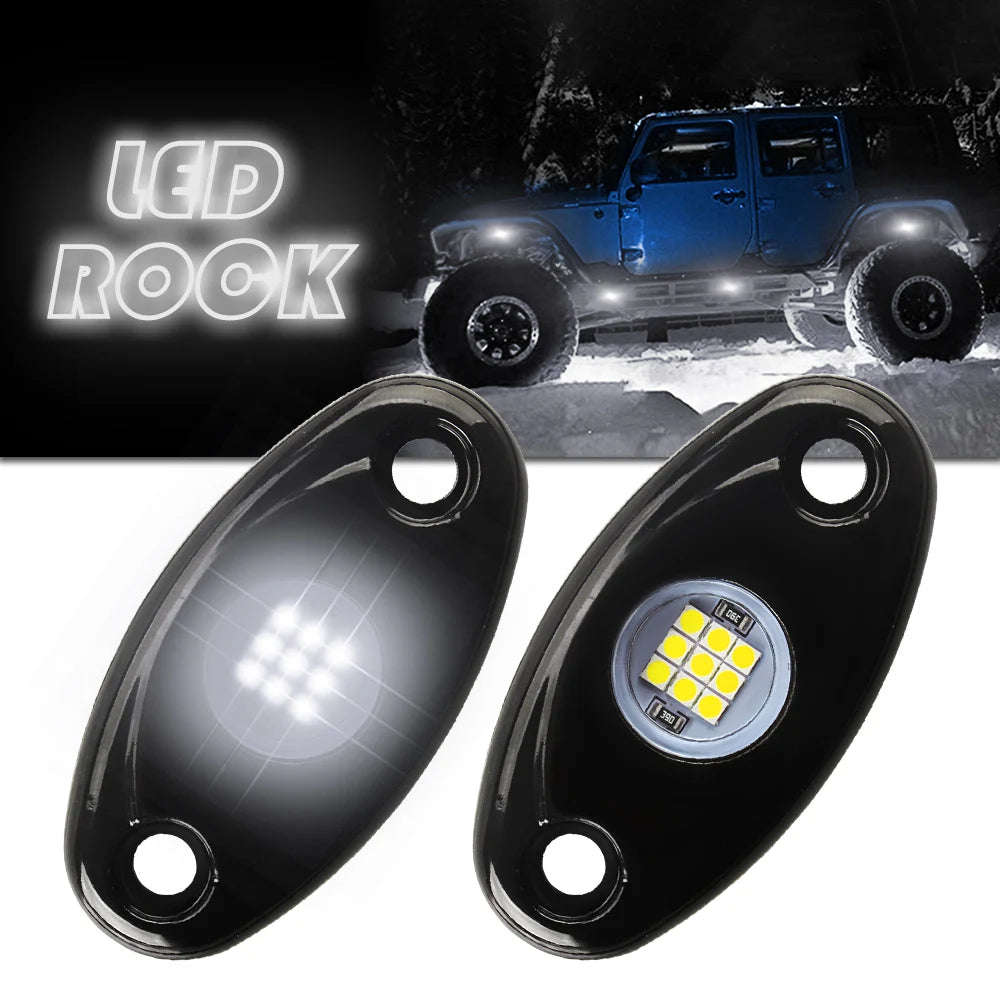 Pair of black LED rock lights with yellow illumination shown next to a blue Jeep.