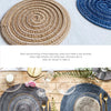Collection de dessous-de-verre et sets de table en tissage rond dans des tons naturels et indigo sur une surface blanche.