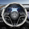 Close-up view of a Mercedes steering wheel with carbon fiber texture covers and digital instrument cluster.