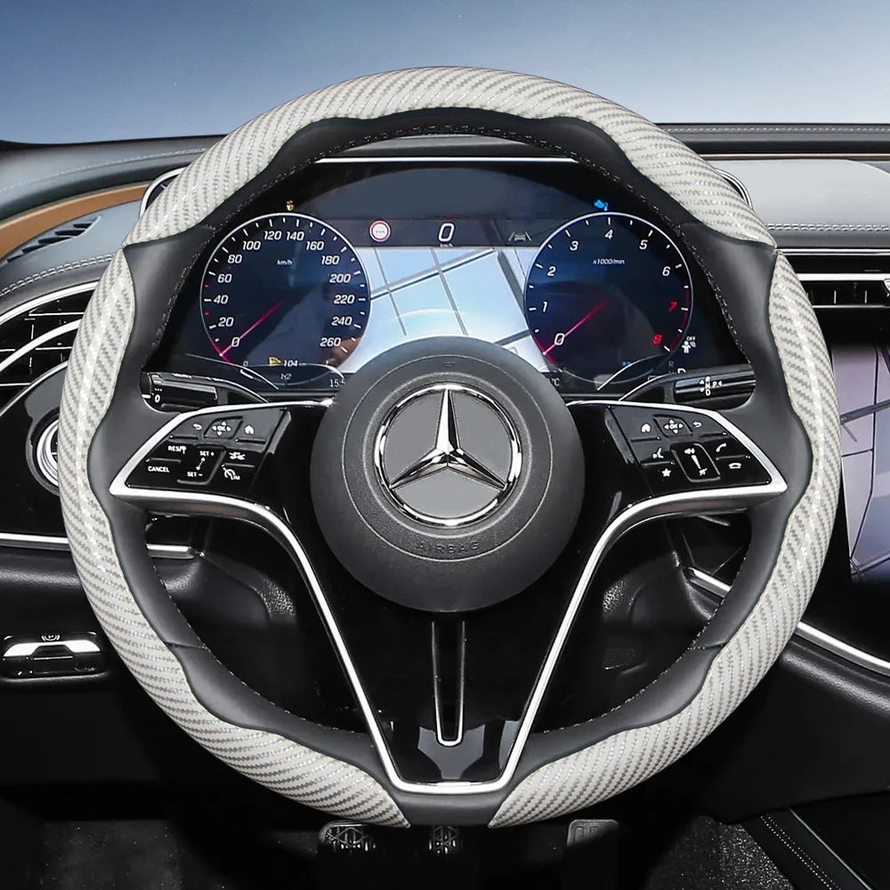 Close-up view of a Mercedes steering wheel with carbon fiber texture covers and digital instrument cluster.