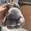 A close-up of a gray plush bunny keychain with soft fur and black and white checkered ears attached to a gold ring.